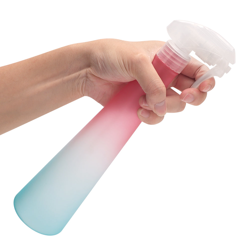 rainbow hair spray bottle pink and green being tilted and used